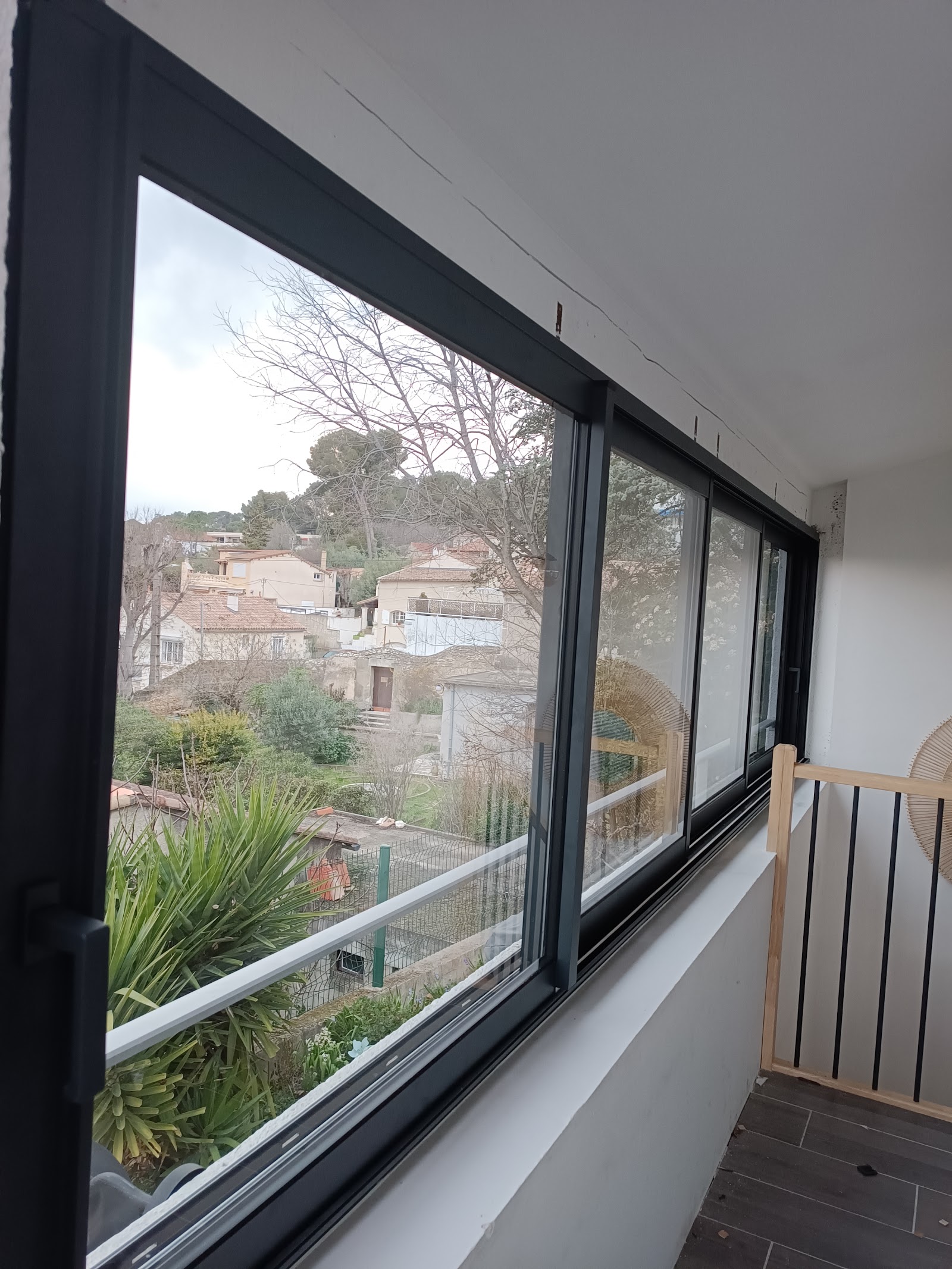 Grande fenêtre panoramique en aluminium ouvrant sur un village